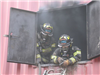 Firefighters leaning out of smoke filled window