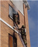 Firefighter climbing into building from ladder