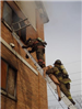 FIrefighters climbing down ladder with mannequin