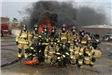 Firefighters in full gear posing in front of fire